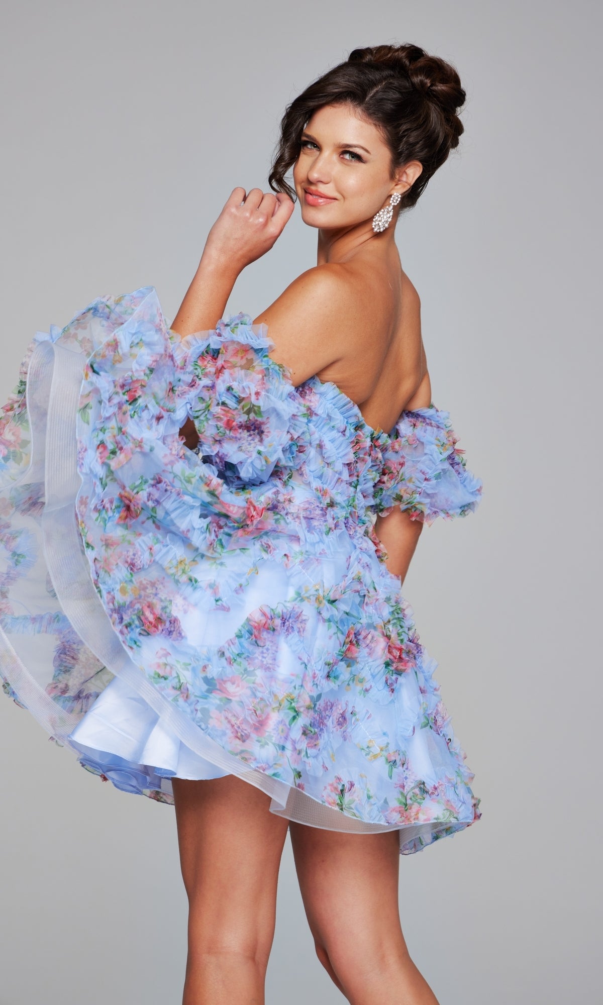Model poses with one hand near her face, wearing the Jovani Puff-Sleeve Short Print Hoco Dress 42573 against a plain gray background.